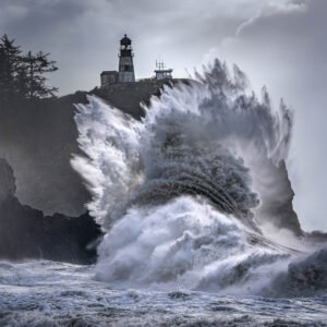 A giant waves explodes on the rocks beneath the Cape Disappointment Lighthouse