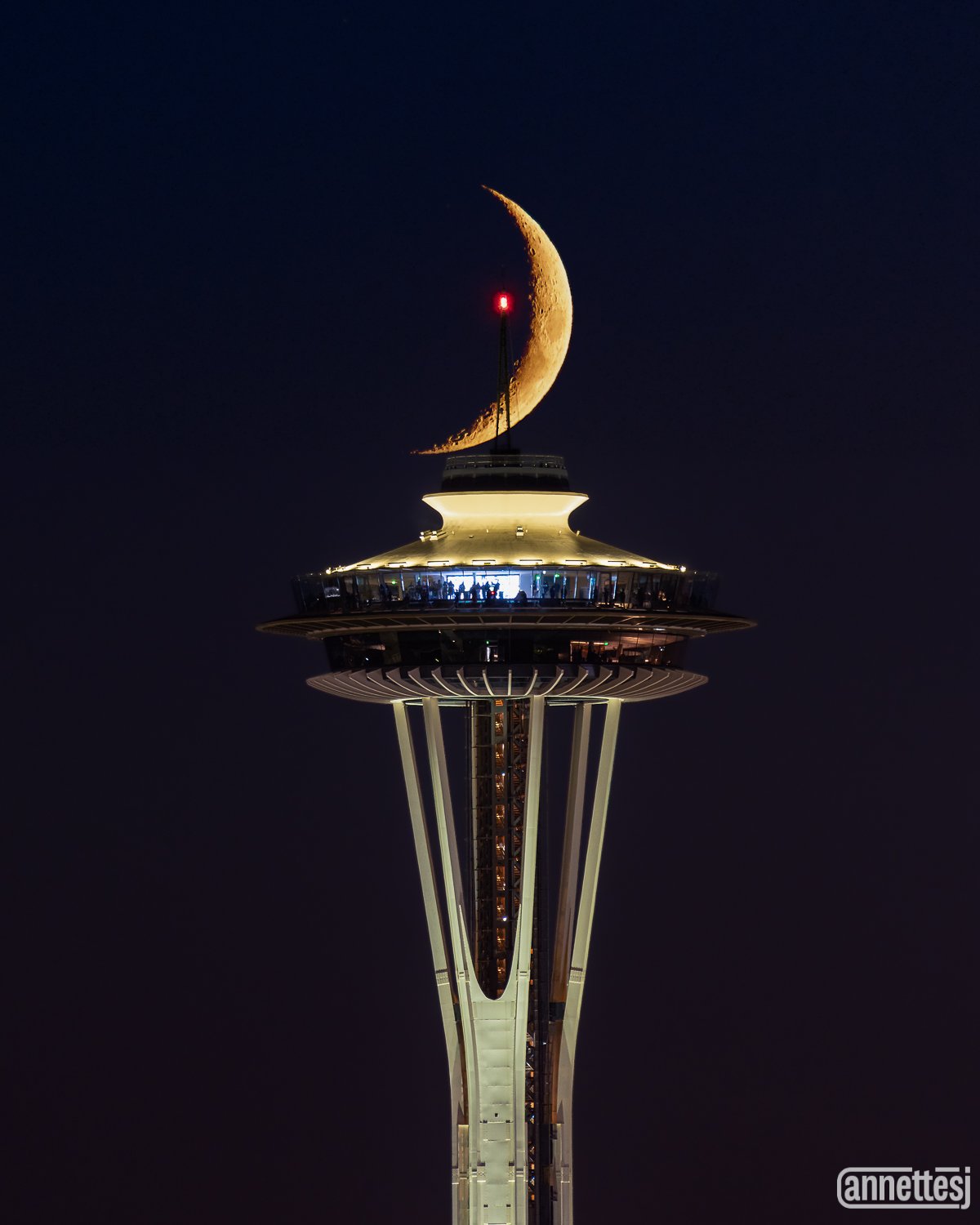 The crescent moon aligns with the Space Needle.